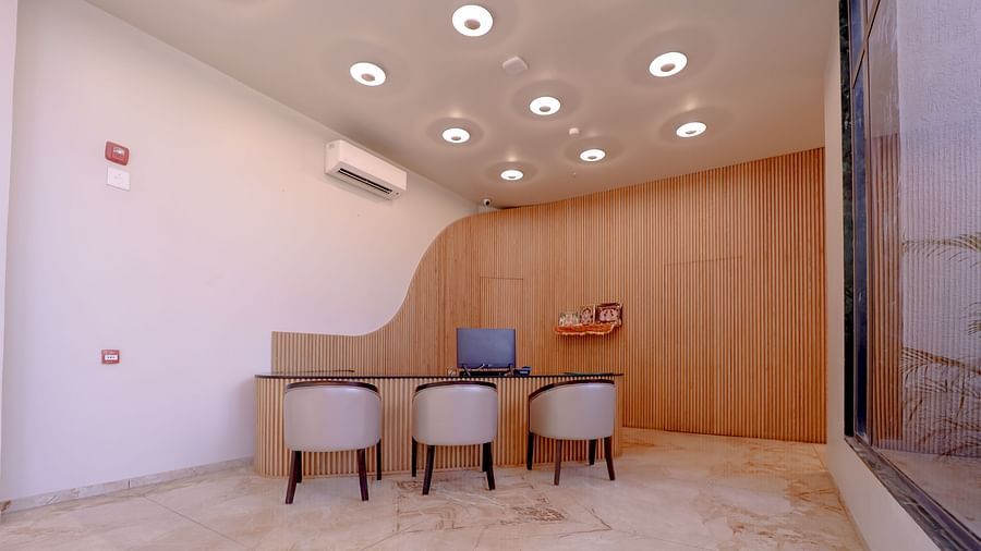 An image of a reception lobby featuring a reception desk and chairs around it, and ceiling lights on top - Pride Resort Ambaji